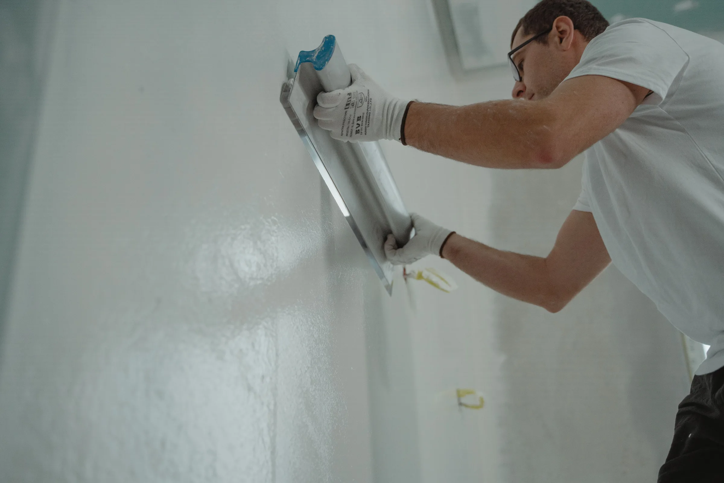 A worker in gloves applying a finish to an interior wall