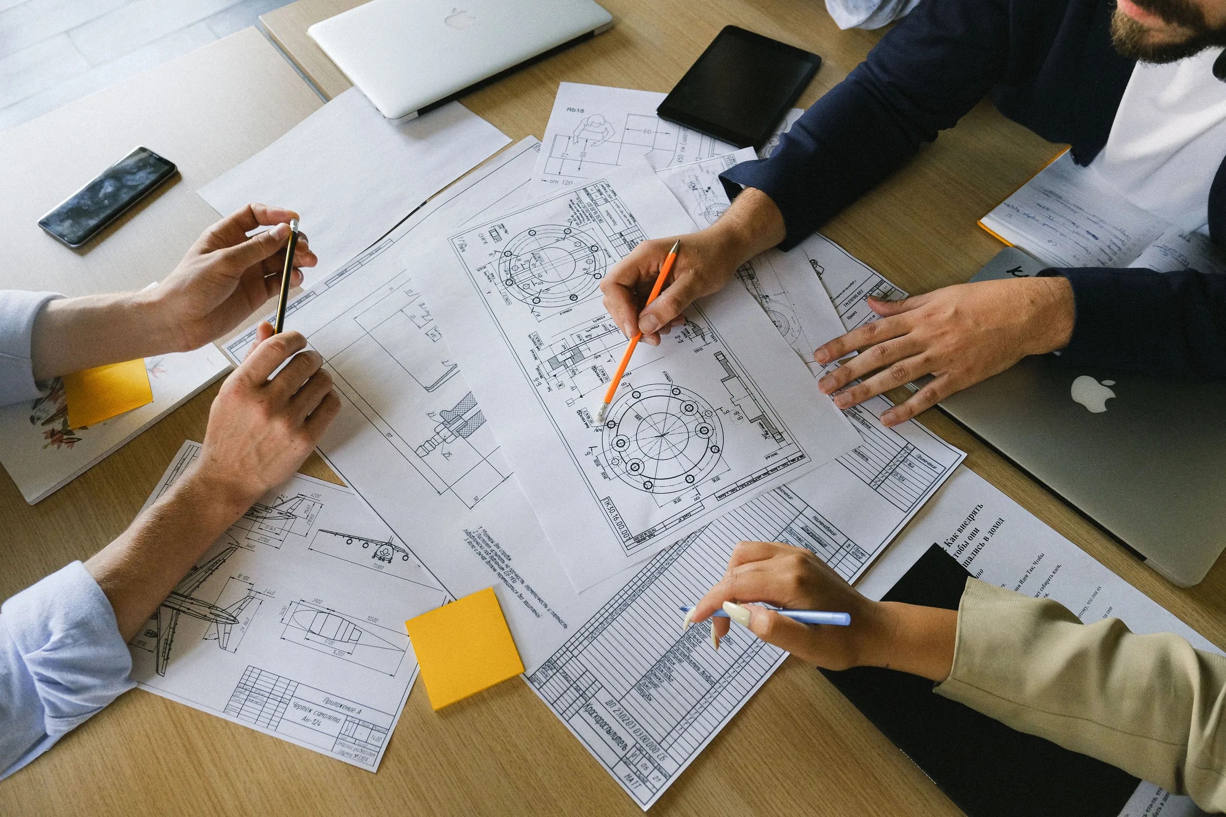 A team around a desk working over building plans and drawings